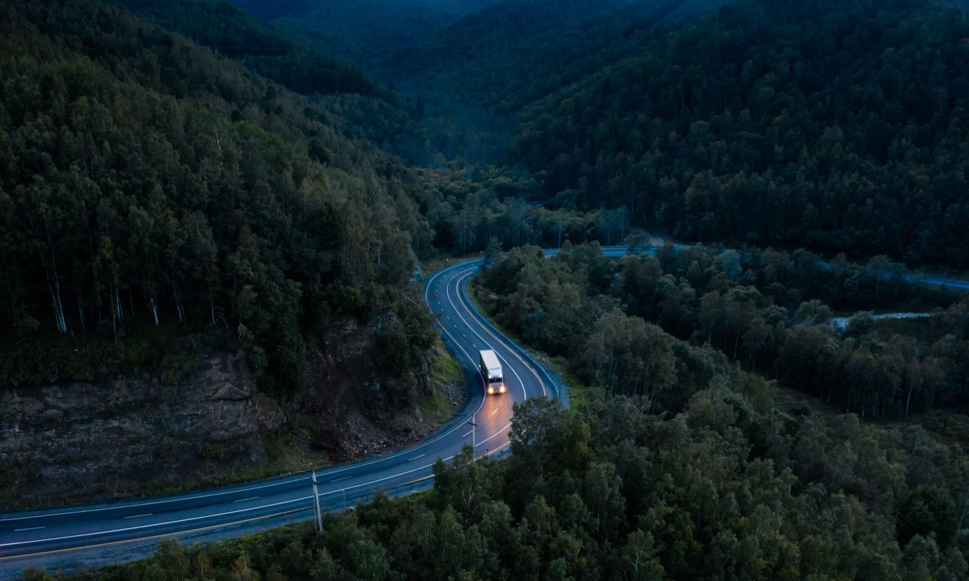 Aerial view of a sharp turn on a mountain road among green forest